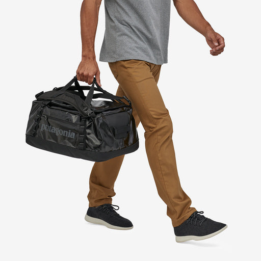 Patagonia Black Hole Duffel — 40L, black, hand carry view on model.