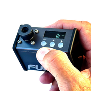 Hand holding a small electronic device with a digital display and control buttons, branded 'Ful'.