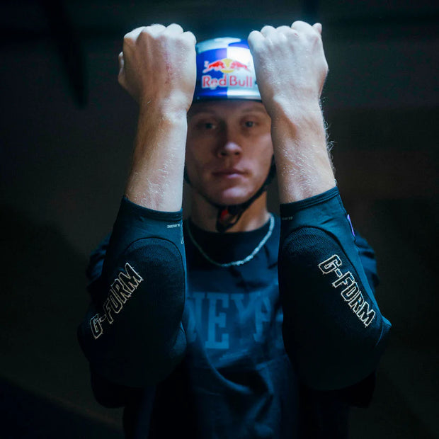Person wearing a helmet with a Red Bull logo on it, against a dark background