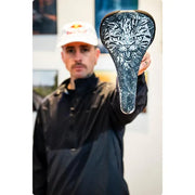 Man holding a bicycle seat with a tiger design outdoors