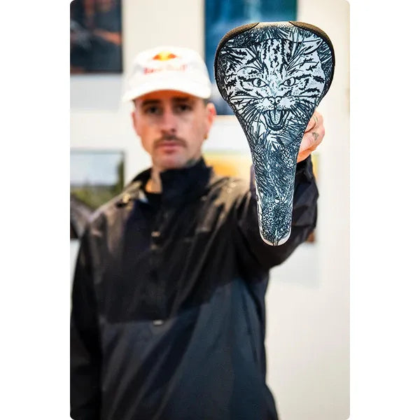 Man holding a bicycle seat with a tiger design outdoors