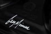 Close-up of a black surface with a signature-style text and logo.