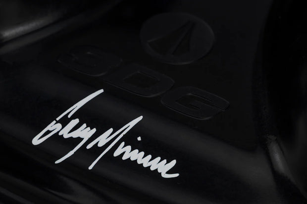 Close-up of a black surface with a signature-style text and logo.