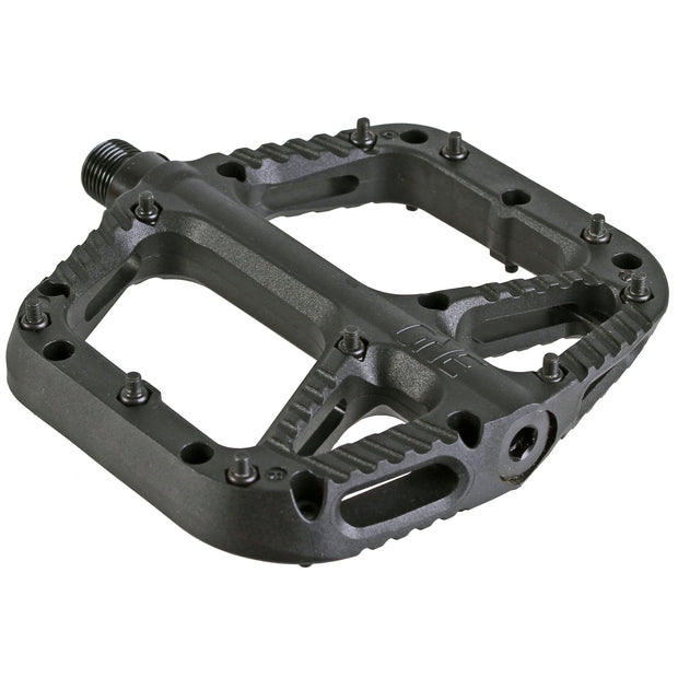 A black OneUp Components Comp Platform Pedal designed for mountain bikes, featuring multiple steel pins for traction and a wide stable platform.
